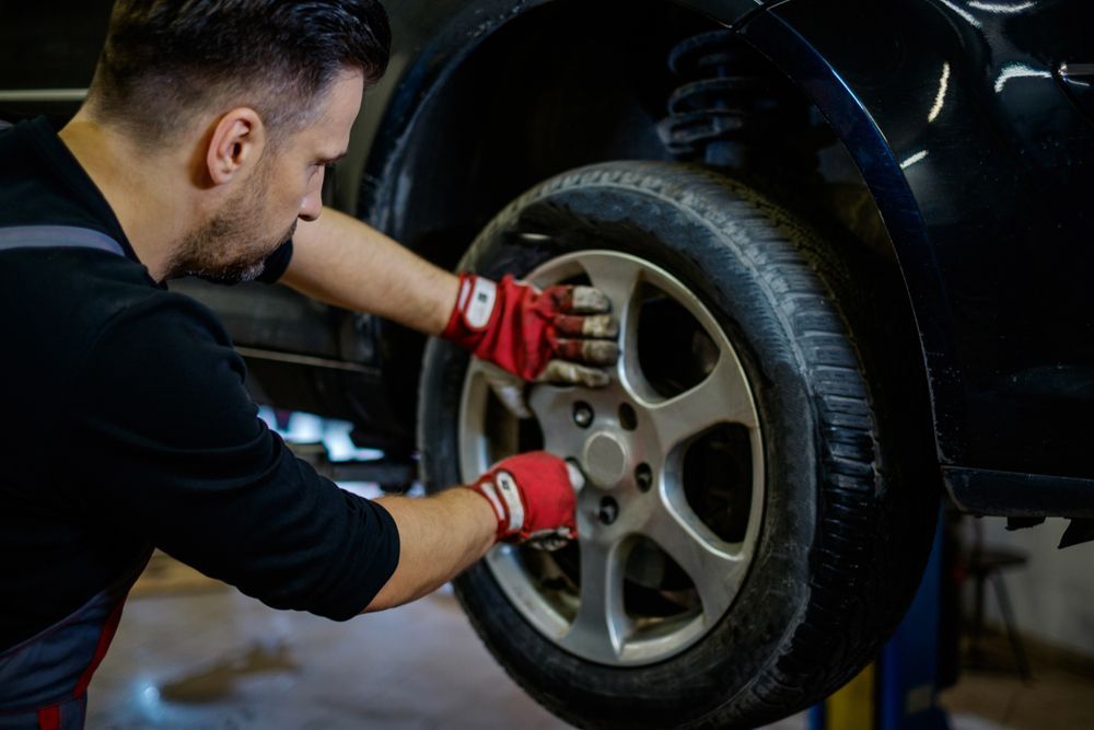 Mechanic Tightening Lug Nuts on a Car Wheel With a Wrench in a Garage — Van Diemen's Automotive & Electrical Repairs In Bellerive, TAS