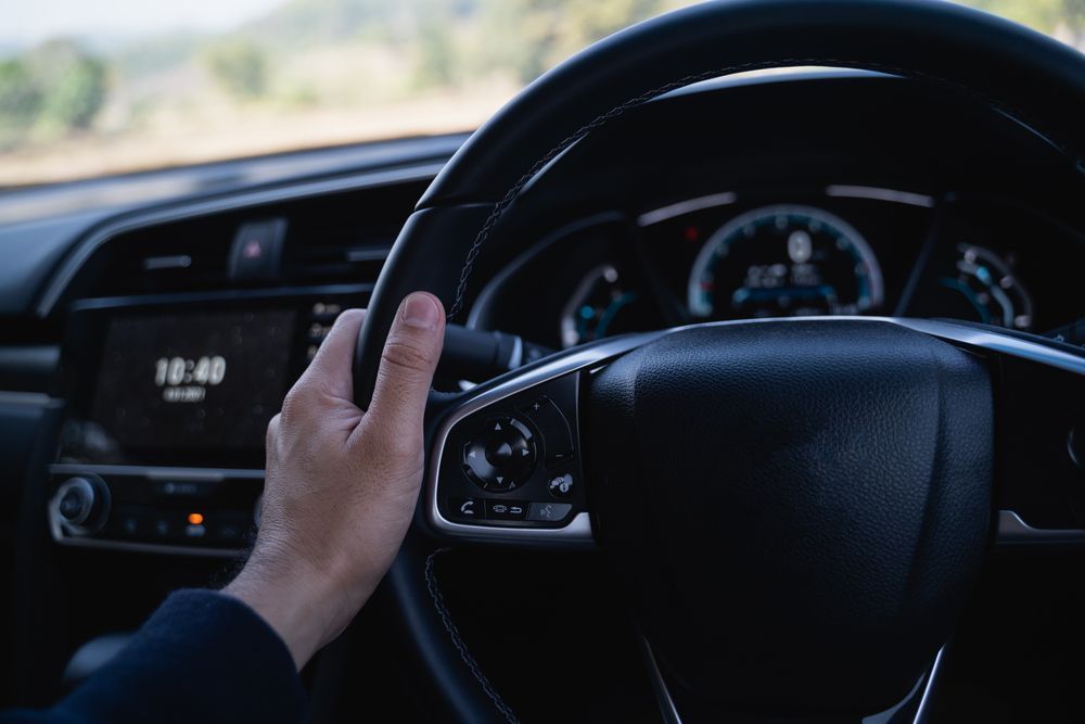 Hand on a Car Steering Wheel, Driving With Dashboard and Road Visible Ahead — Van Diemen's Automotive & Electrical Repairs In Bellerive, TAS