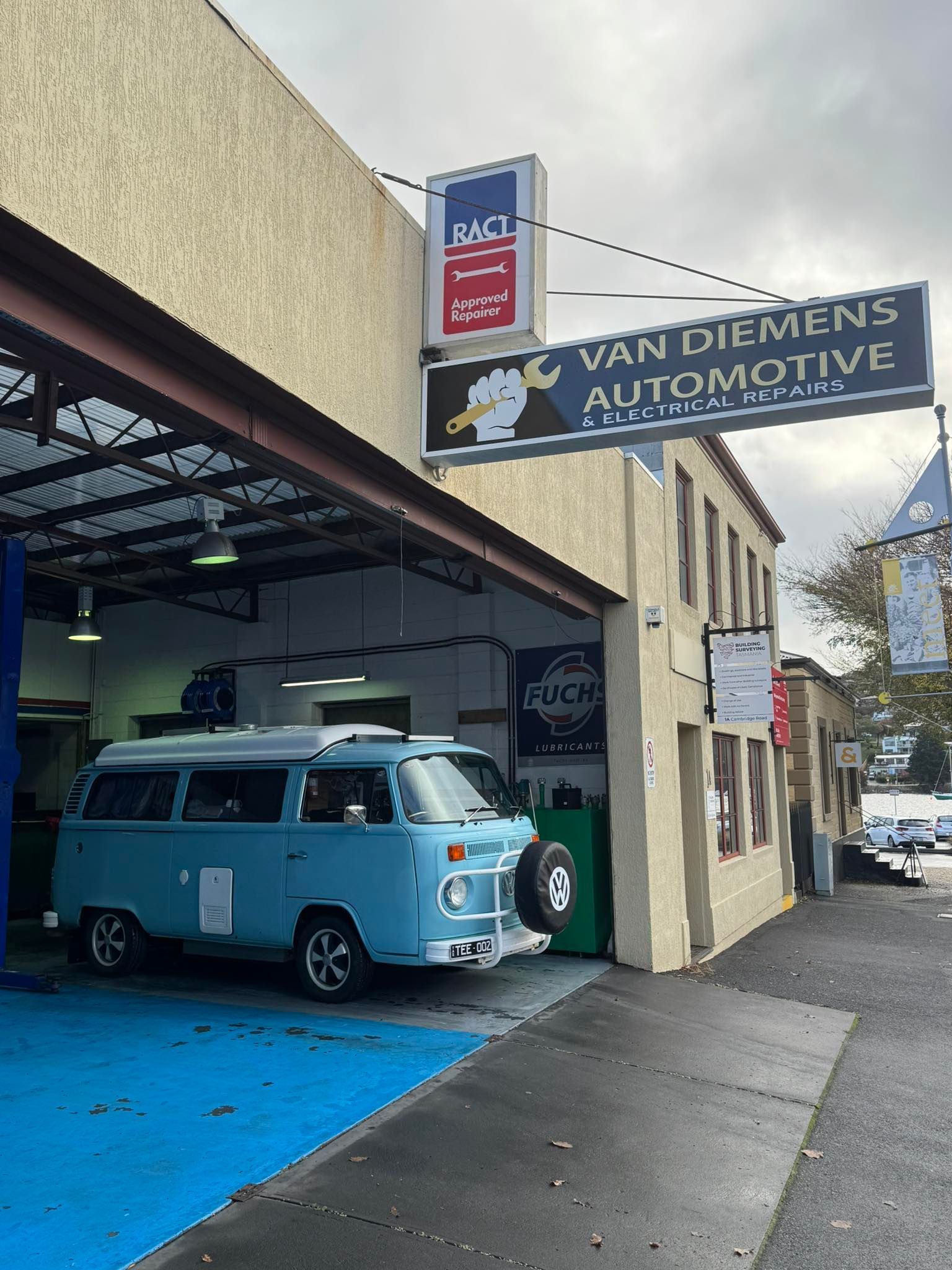 Blue Van Parked Outside Van Demers Automotive Garage With an Open Bay and Sidewalk View — Van Diemen's Automotive & Electrical Repairs In Bellerive, TAS
