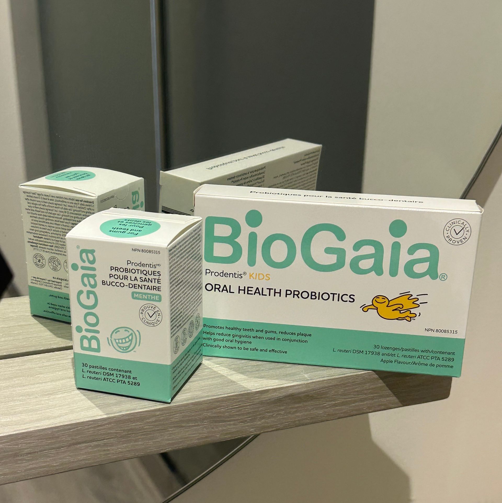 BioGaia oral health probiotic boxes on a surface, featuring white and teal packaging with text and a cartoon chick.