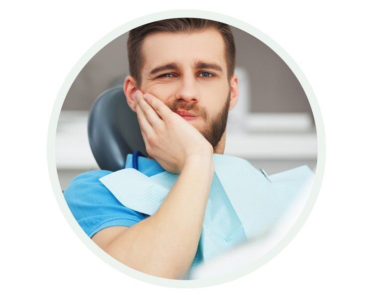Man in a dentist chair, holding cheek in pain, wearing a blue shirt.