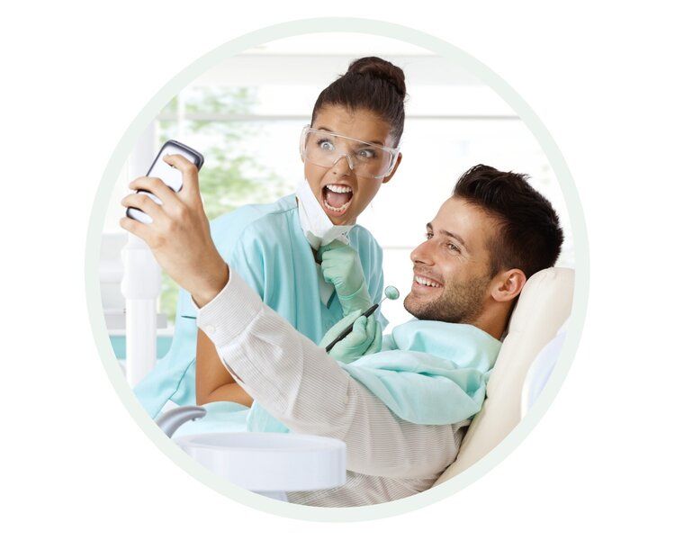 Dentist and patient taking a selfie in the dental chair. Both smile, excited in the brightly lit office.