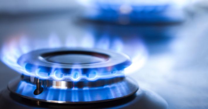 Blue flames of an ignited gas stove burner in close-up view.