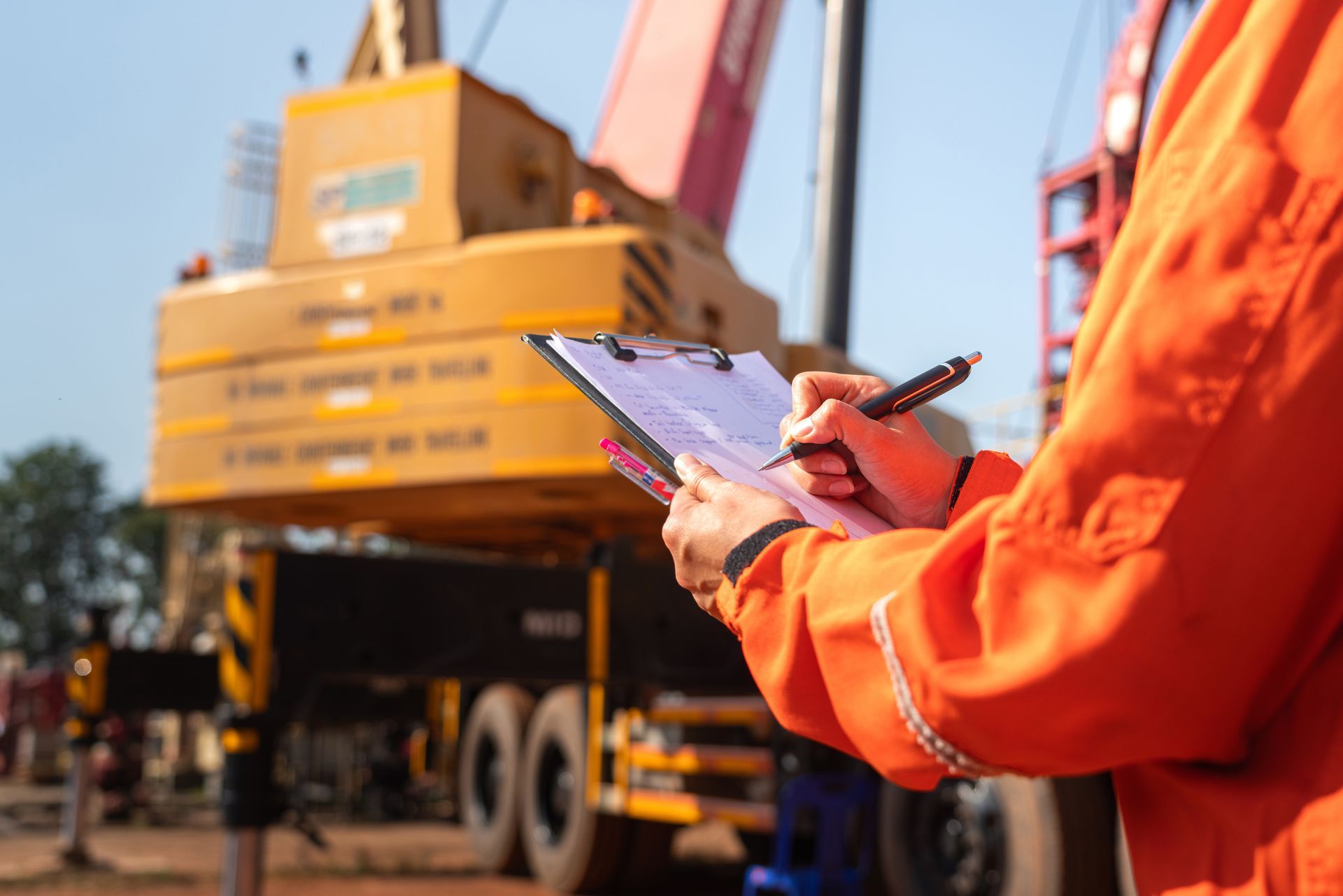 Construction site supervisor completing an inspection checklist near a crane.