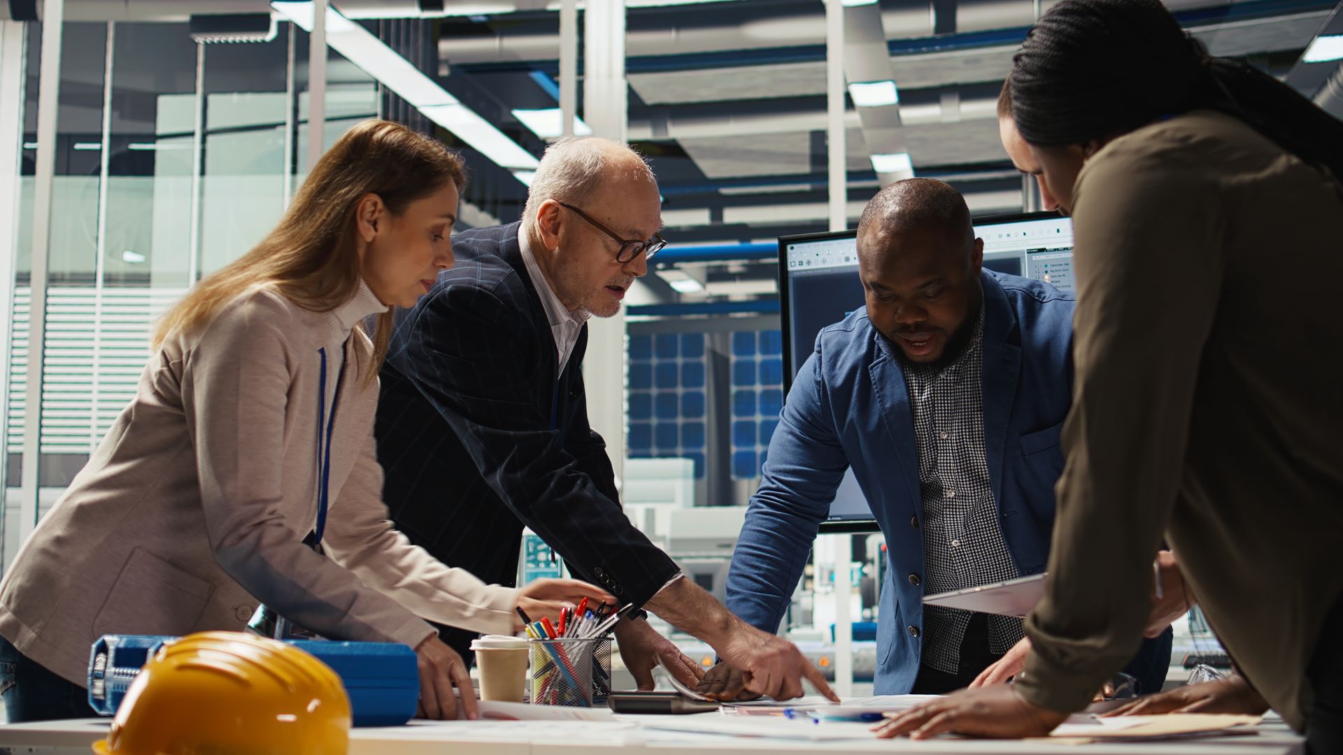Team collaborating over blueprints at a construction site, with hard hats and a building model on the table