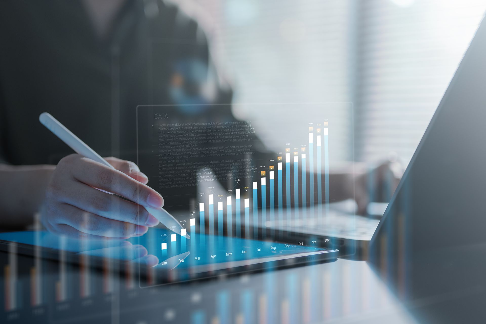 Hand using stylus on tablet with glowing bar chart overlay in a modern office