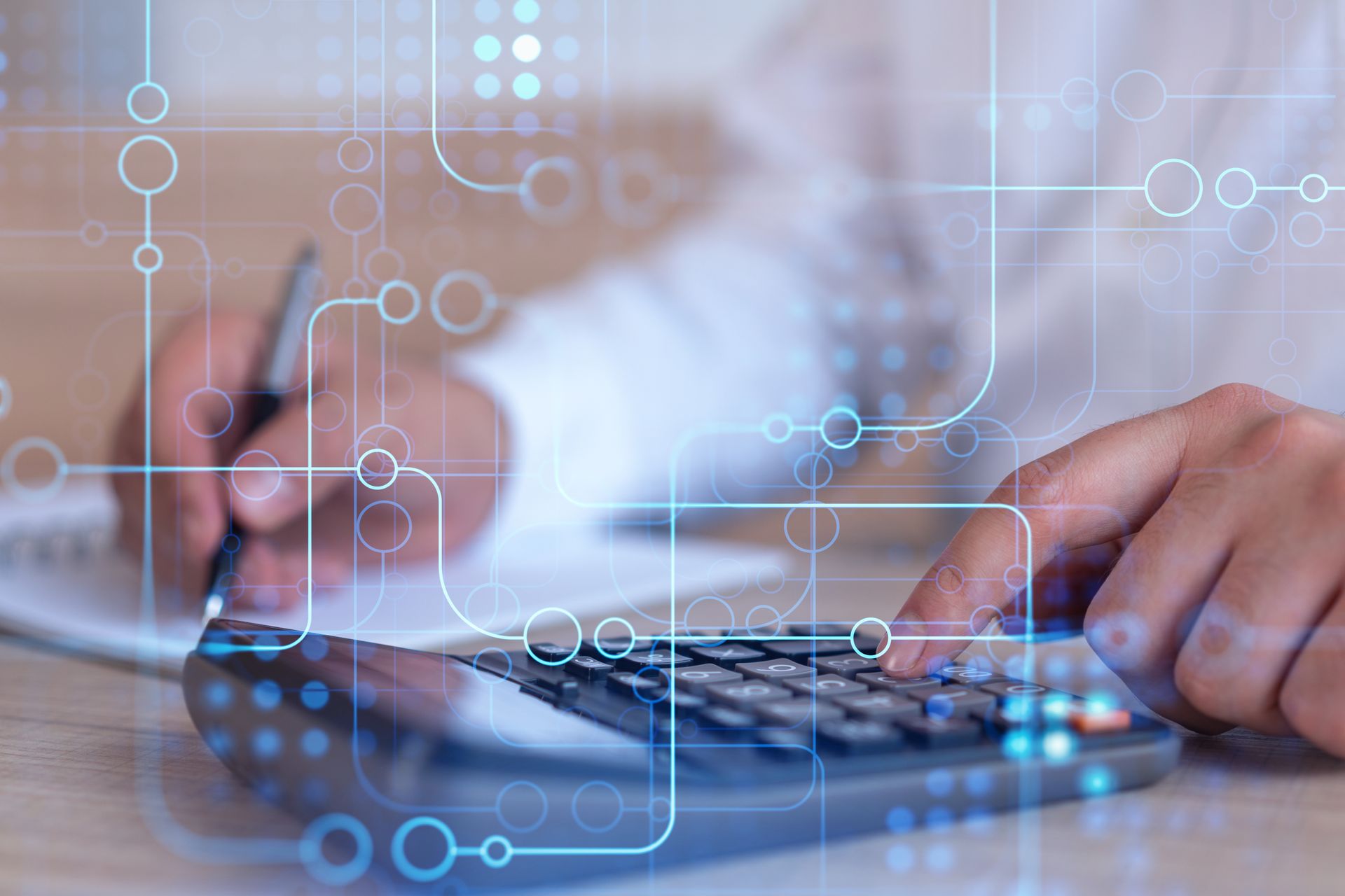 Hands using a calculator and pen over paperwork with blue digital interface icons overlaying the scene