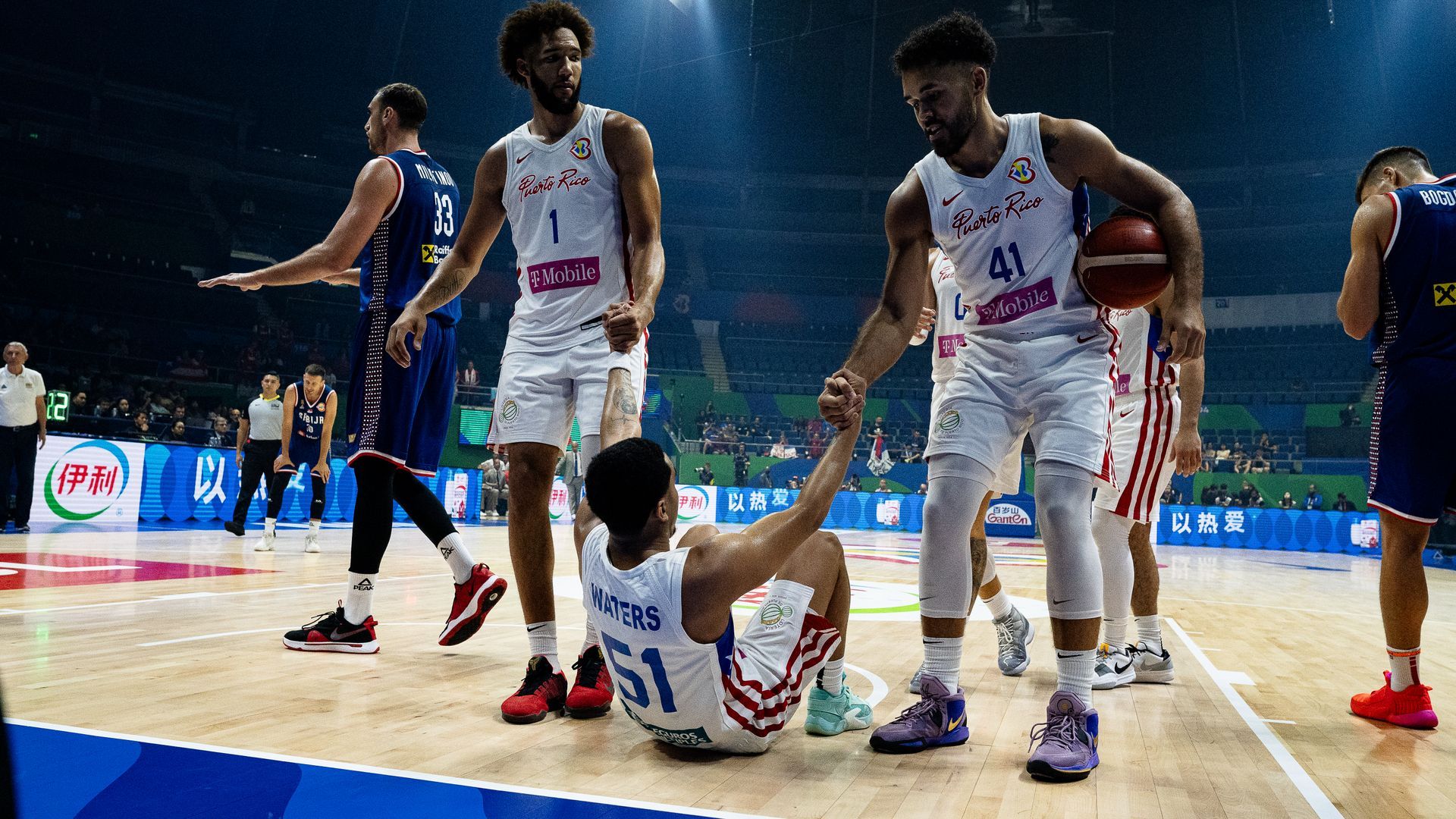 Basketball players in white uniforms surround a fallen teammate on the court during a game