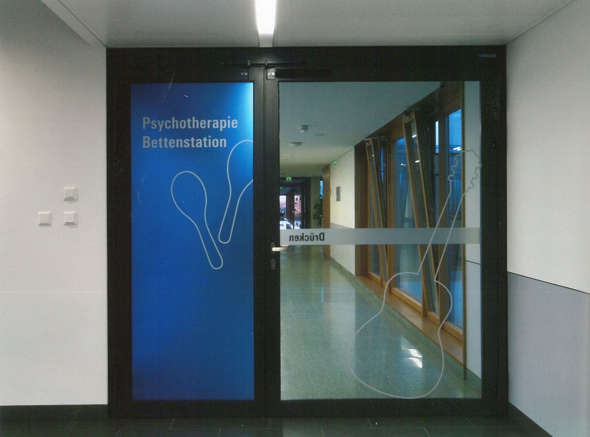 Ingresso in vetro del Centro di Psicoterapia con insegna blu e corridoio oltre
