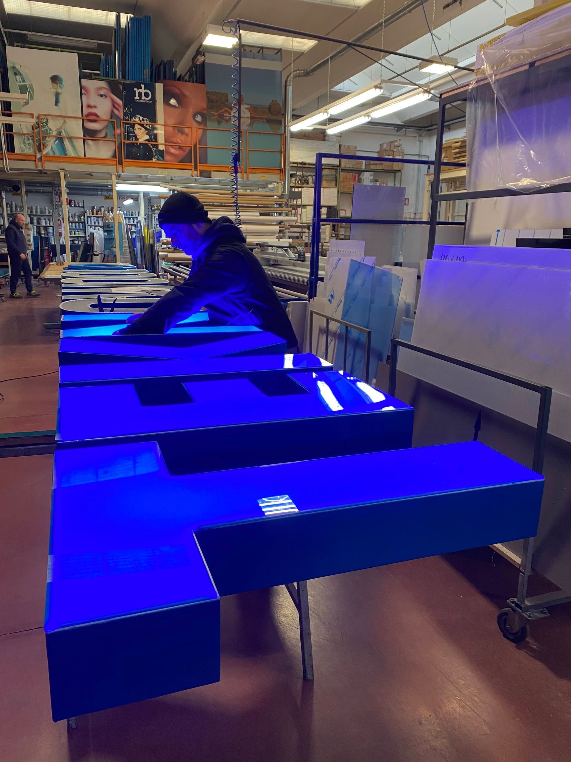 Persona che sistema grandi pannelli di schiuma blu in un'officina o in un magazzino.