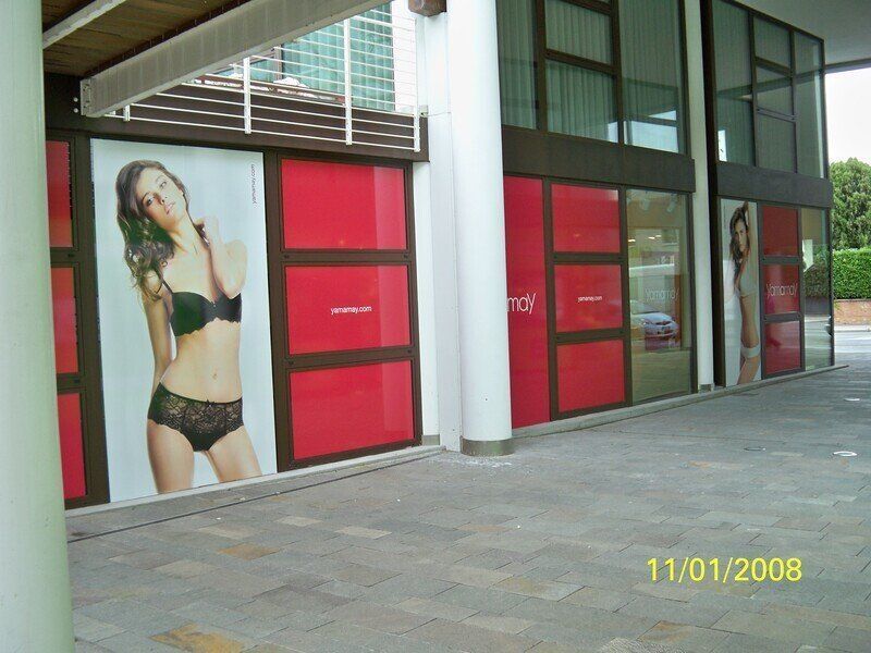 Vetrina con grandi poster di moda e pannelli di vetro rosso all'esterno di un edificio
