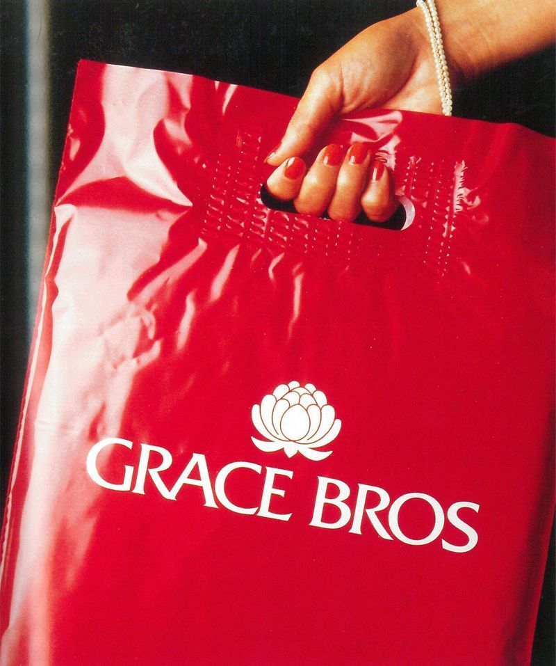 Borsa della spesa rossa di Grace Bros tenuta in mano