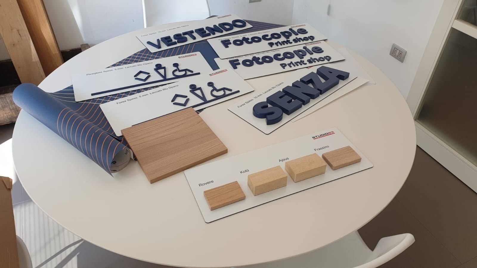 Materiali in Braille e per la comunicazione tattile disposti su un tavolo rotondo bianco.