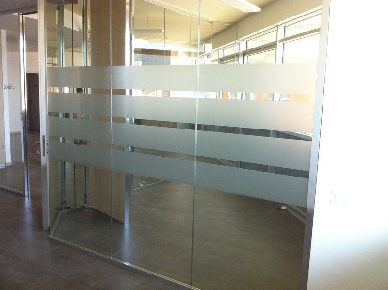 Ingresso dell'ufficio in vetro con strisce orizzontali satinate e cornice metallica.