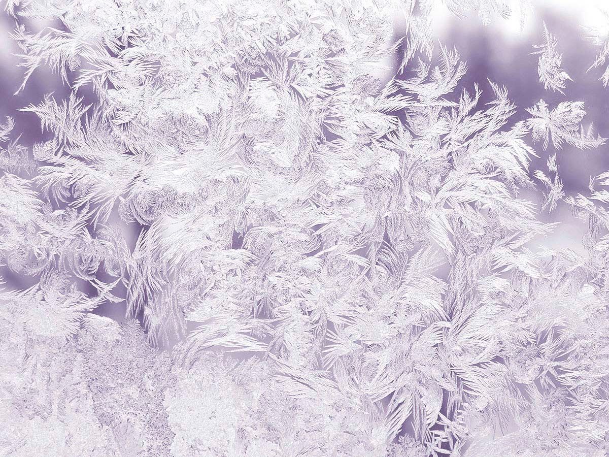 Primo piano di cristalli di ghiaccio color lilla pallido che formano un delicato disegno a fiocco di neve.