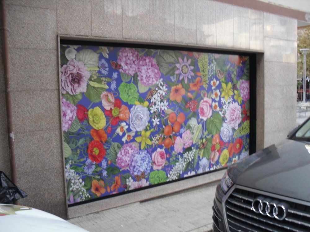Murale floreale colorato in una nicchia a muro accanto a un'Audi parcheggiata