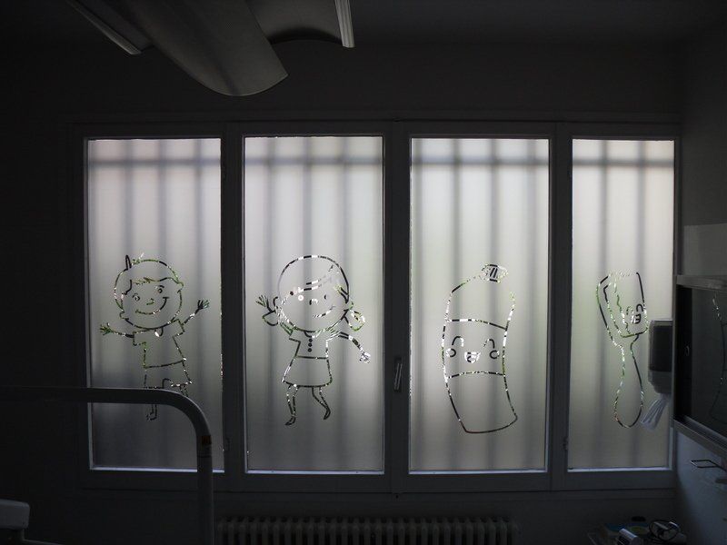Parete in vetro satinato con semplici disegni in stile cartone animato in una stanza scarsamente illuminata