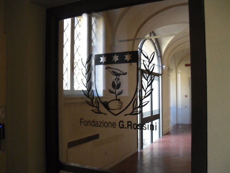 Corridoio con soffitto a volta e finestra, visibile attraverso un vetro con il logo della Fondazione G. Rossini.
