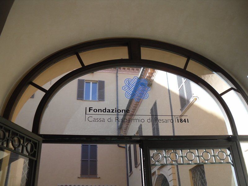 Arched doorway framing a building sign reading “Fondazione Cassa di Risparmio di Pistoia e Pescia.”