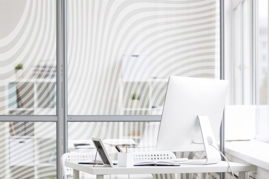 Ufficio luminoso e minimalista con scrivania bianca, computer e grandi tende alle finestre.