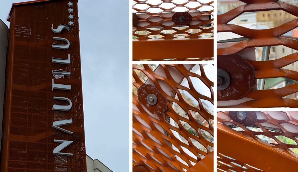 Primo piano dell'insegna Nautilus su una torre color ruggine con reticolo arancione.