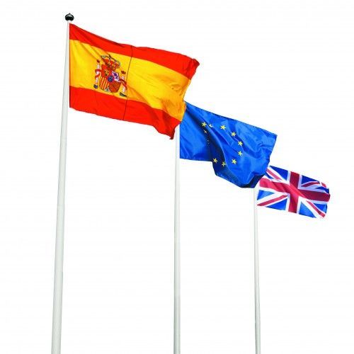 Tre bandiere su aste: Spagna, Unione Europea e Regno Unito su uno sfondo di cielo bianco.