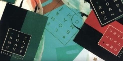 Su un tavolo sono disposti vari poster geometrici colorati con lettere e forme astratte.