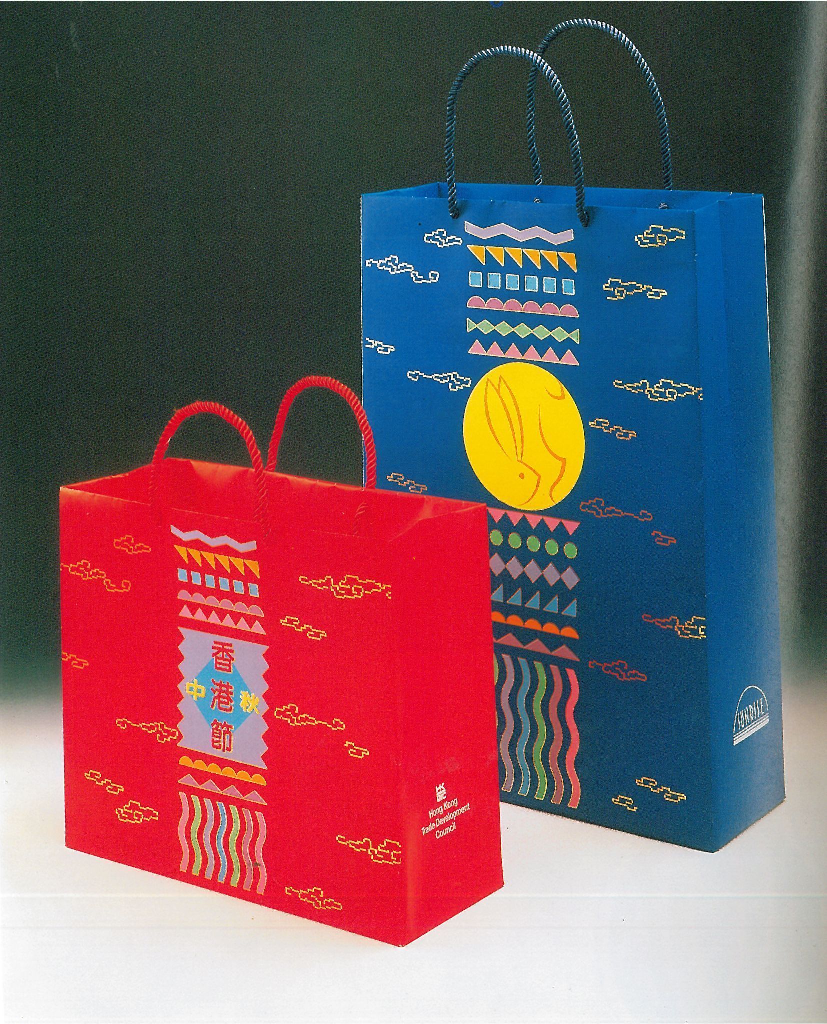 Due sacchetti regalo colorati, uno rosso e uno blu, sono posizionati uno accanto all'altro su una superficie bianca.