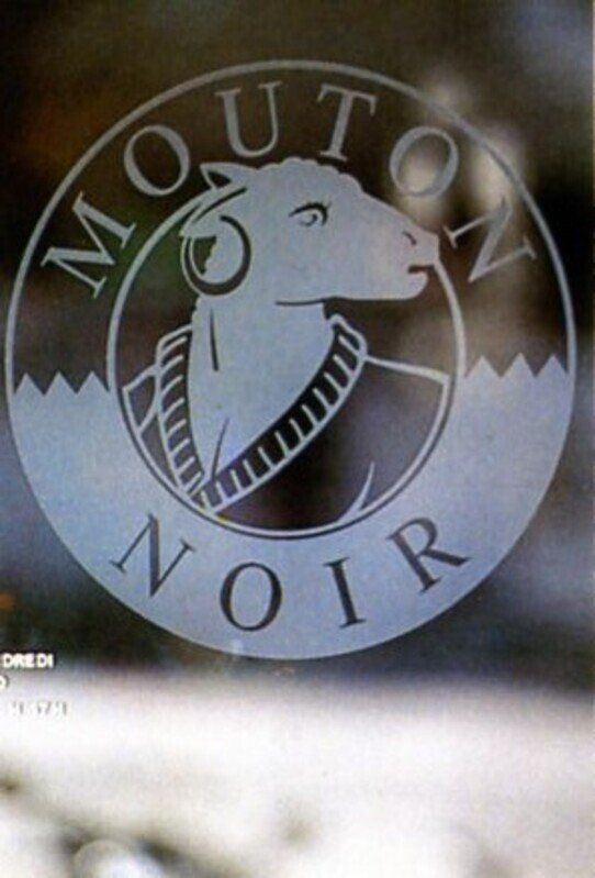 Logo di Mouton Noir con una testa di pecora all'interno di un emblema circolare su sfondo scuro.