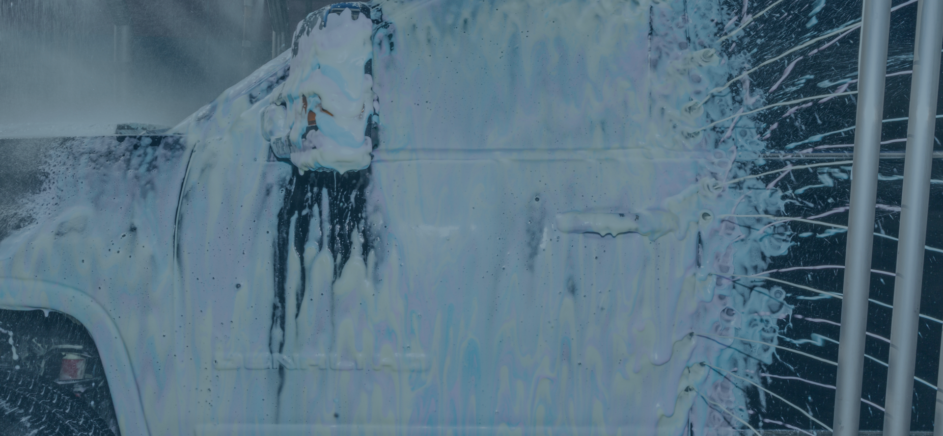 A car is being washed with foam in a car wash.