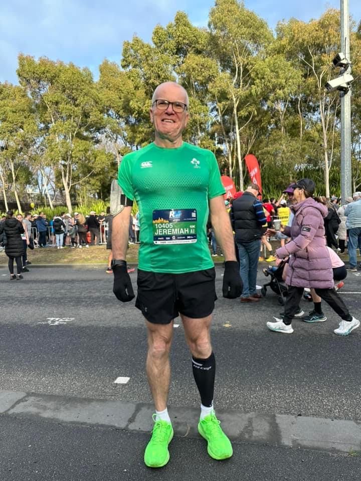 An older man in a green compression shirt, running a race.