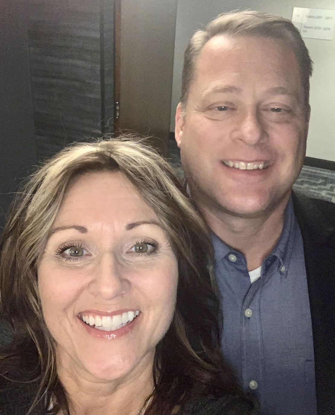 a man and a woman are smiling in front of a sign