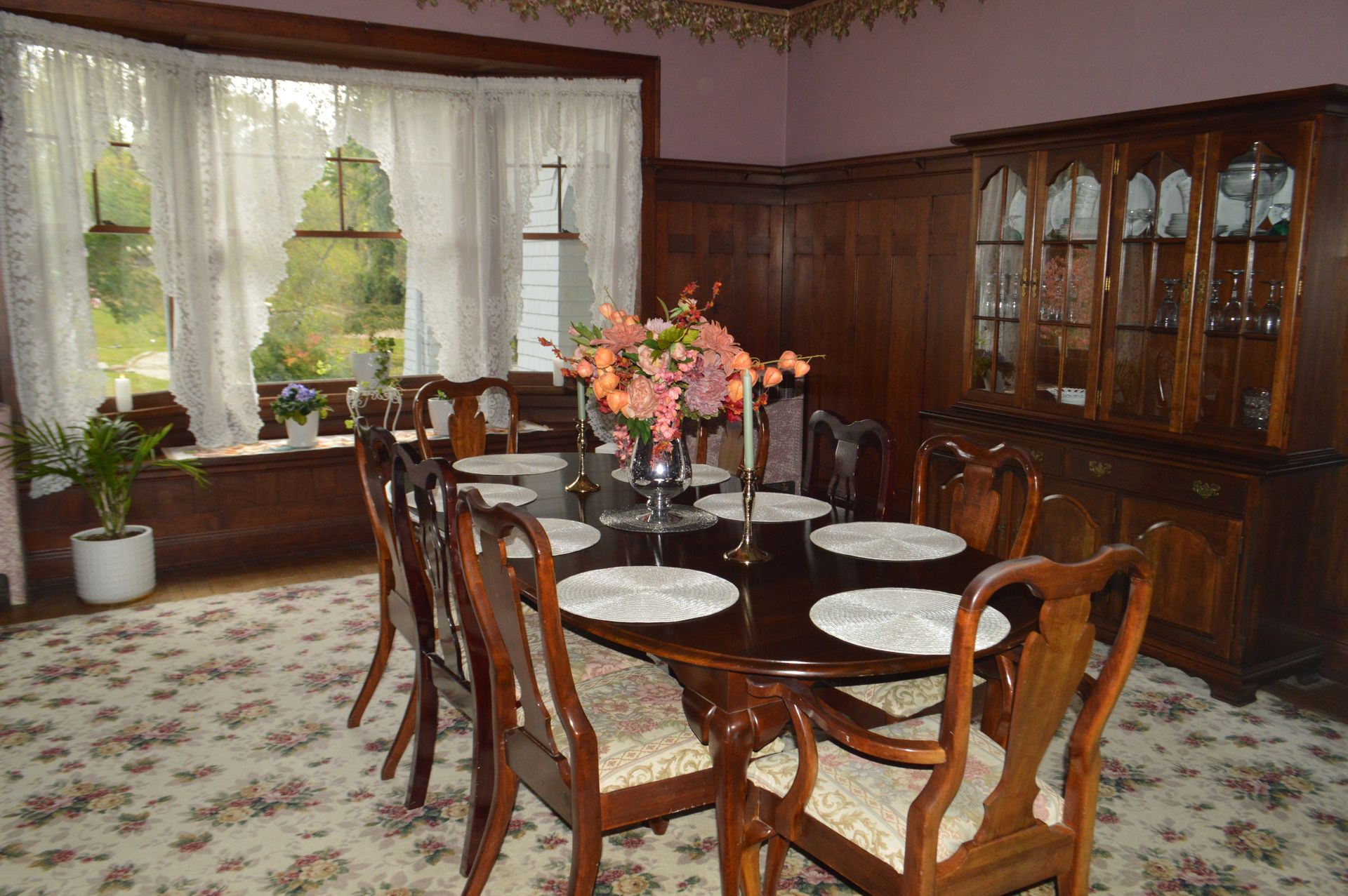 a dining room with a table and chairs and a vase of flowers