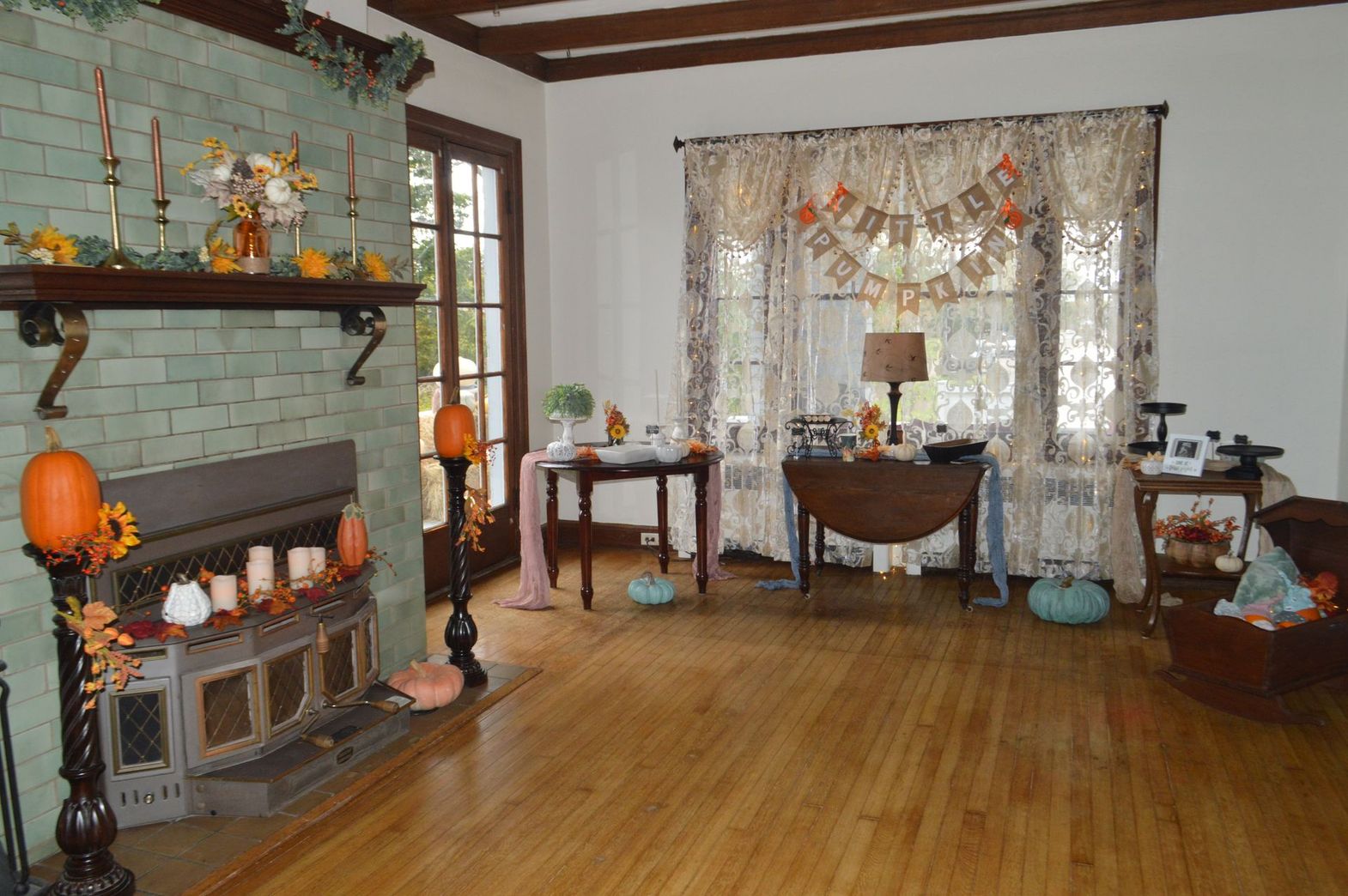 a living room decorated for fall with pumpkins candles and a banner that says happy halloween