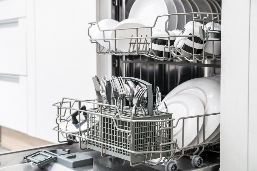 A Dishwasher is Filled With Plates, Cups, and Silverware — Spitfire Chemicals Pty Ltd in Rutherford, NSW
