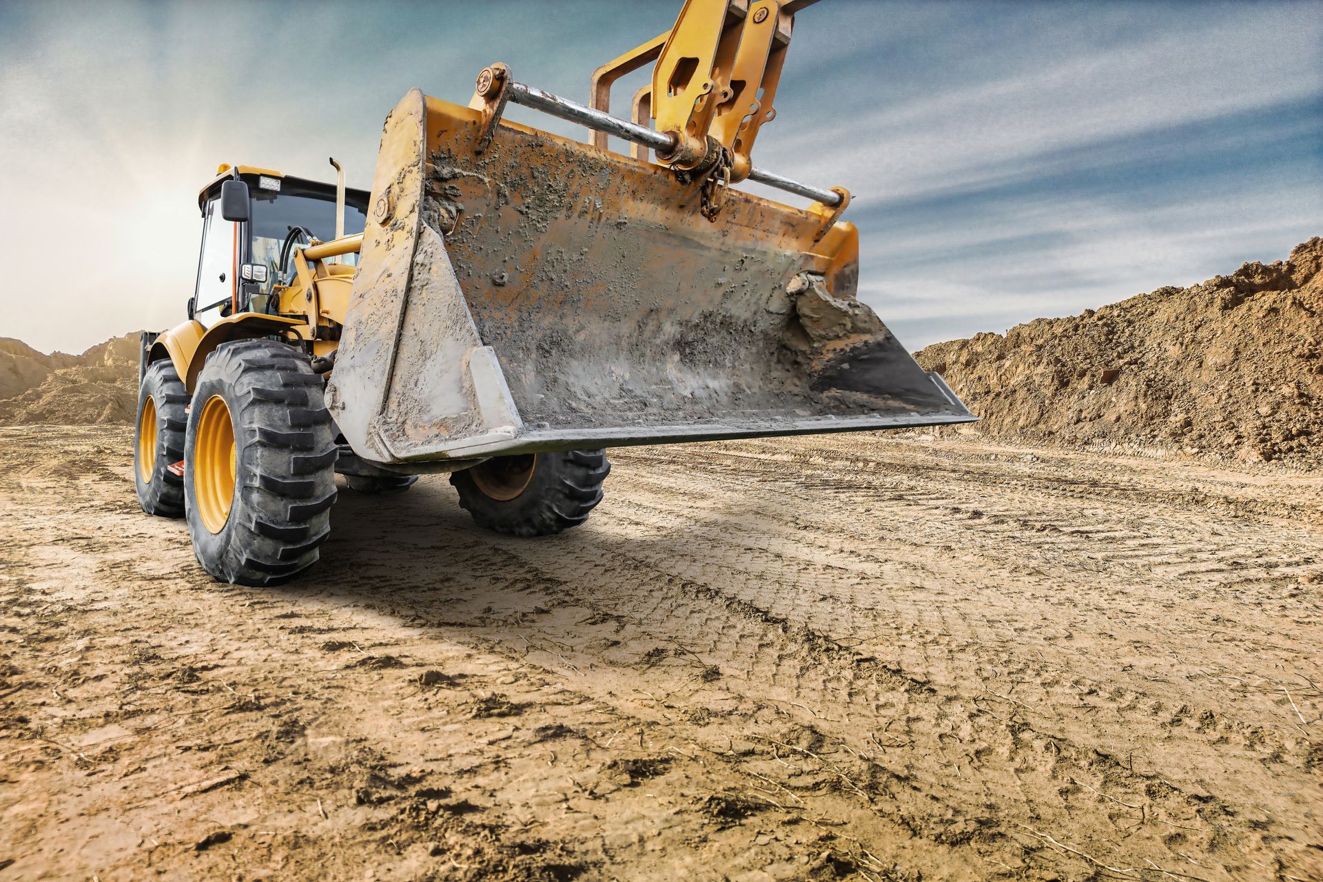 Yellow wheel loader bucket on a dirt job site, equipment rental services Yellow wheel loader bucket on a dirt job site, equipment rental services