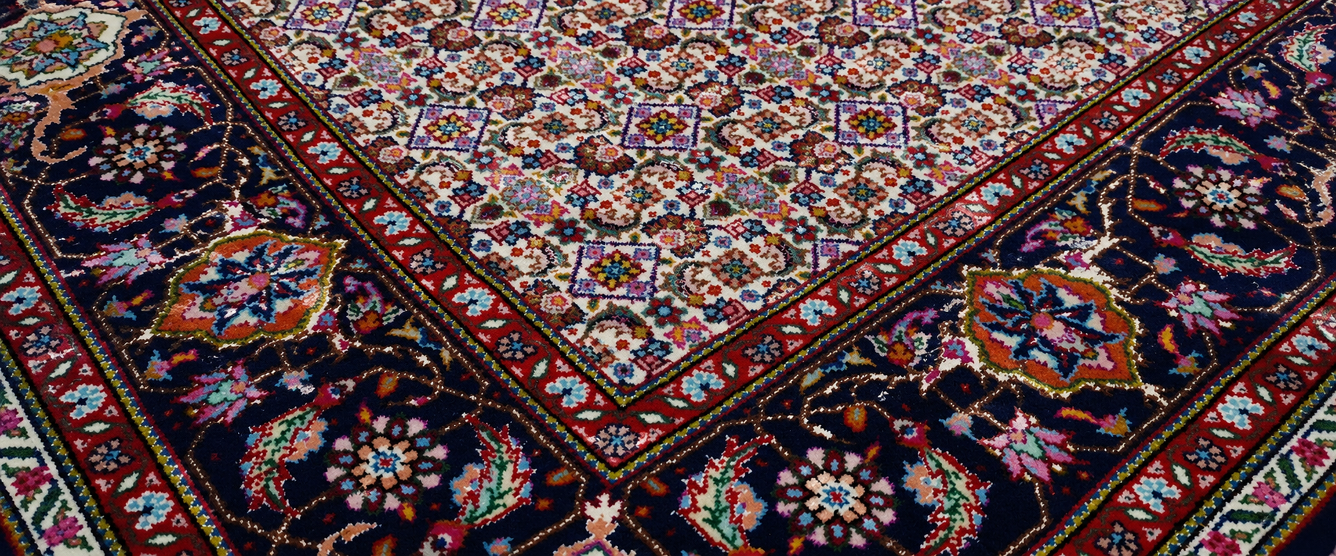 Patterned beige and brown hand-knotted rug with geometric diamonds on a wooden floor