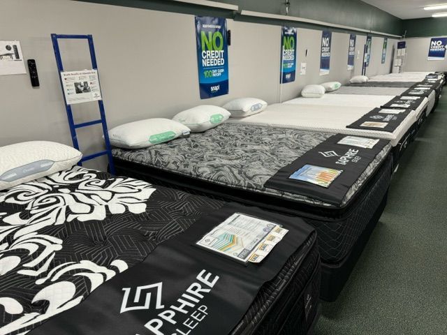 Mattress store interior with several displayed beds, pillows, and