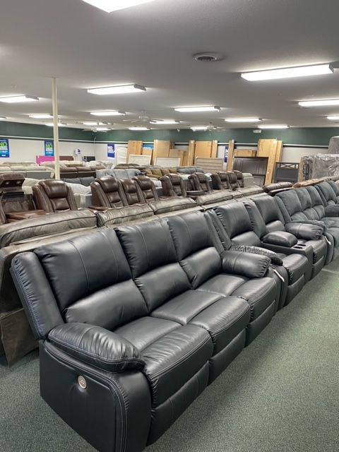 A furniture store interior with rows of black leather recliners on display.