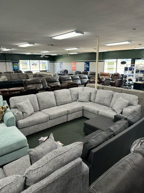 Large furniture showroom with a light grey sectional sofa on display.