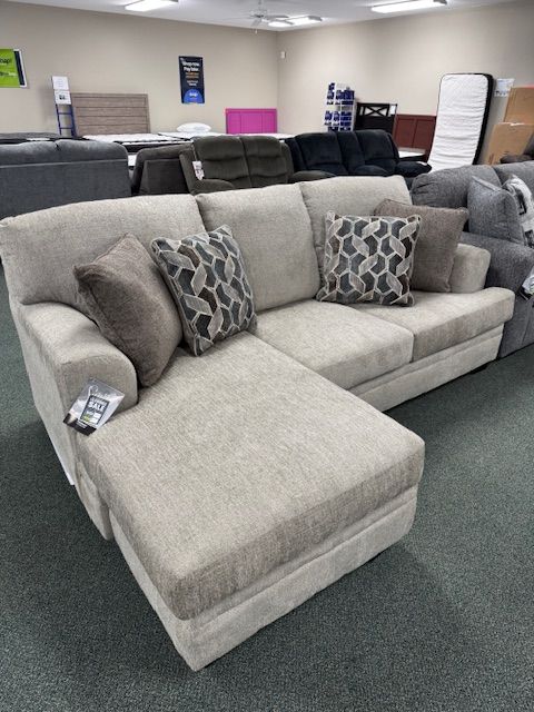 Beige sectional sofa with patterned pillows in a furniture store.