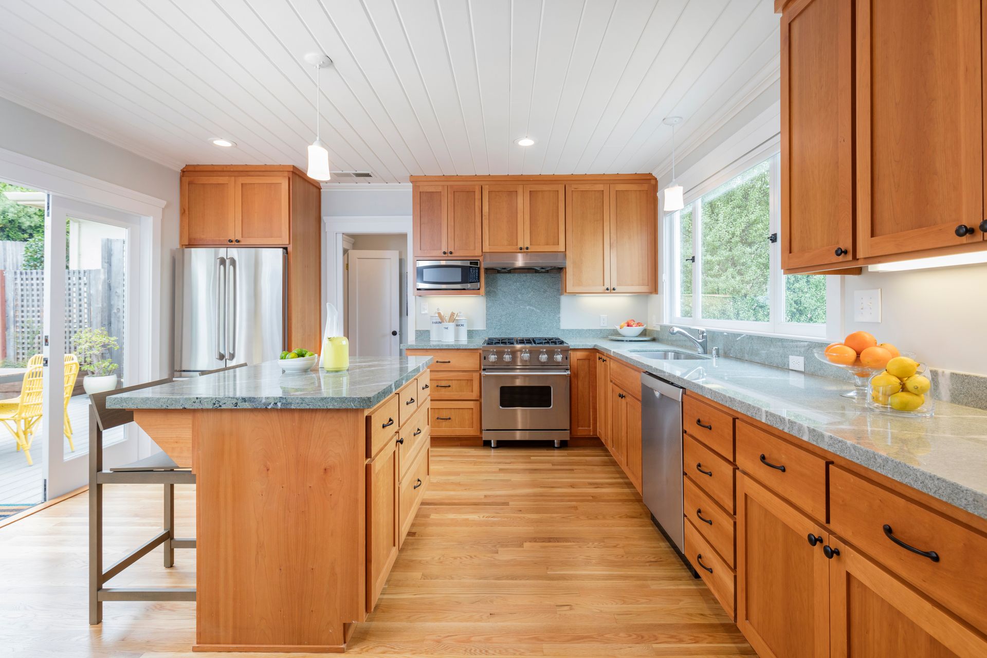 Bright modern kitchen with wood cabinets, stainless appliances, island, and large windows
