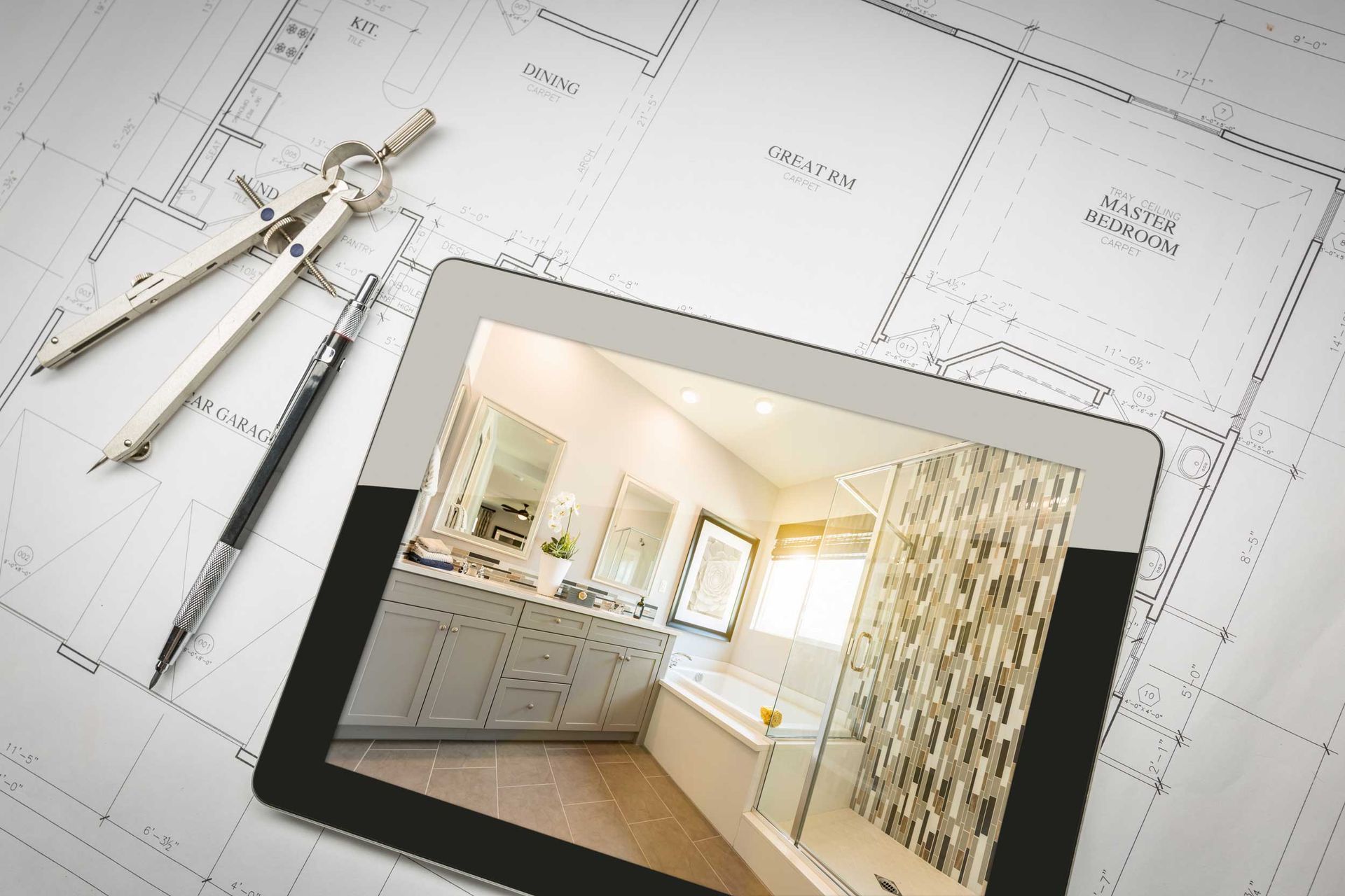 Architectural floor plans with drafting tools and a tablet showing a modern bathroom design