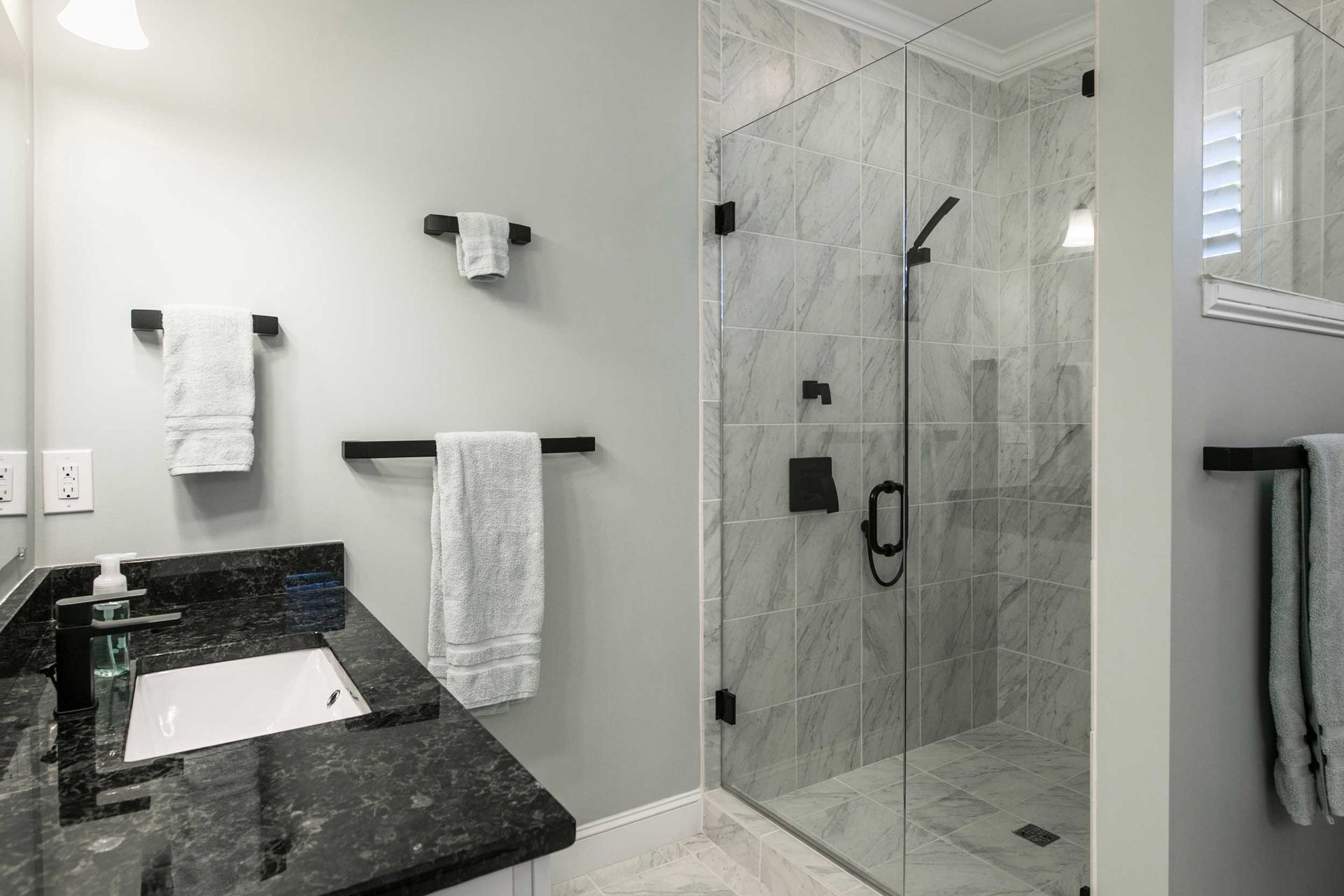 Modern bathroom with glass shower, marble tile walls, and vanity sink. Modern bathroom with glass shower, marble tile walls, and vanity sink.