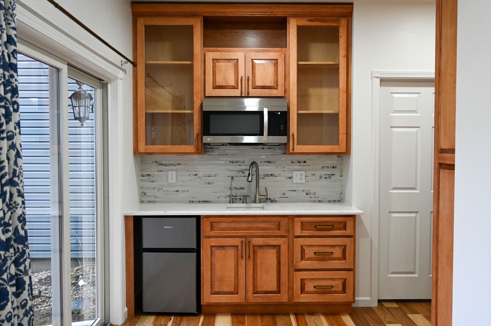 Compact kitchen with wooden cabinets, black appliances, and white backsplash in a bright room