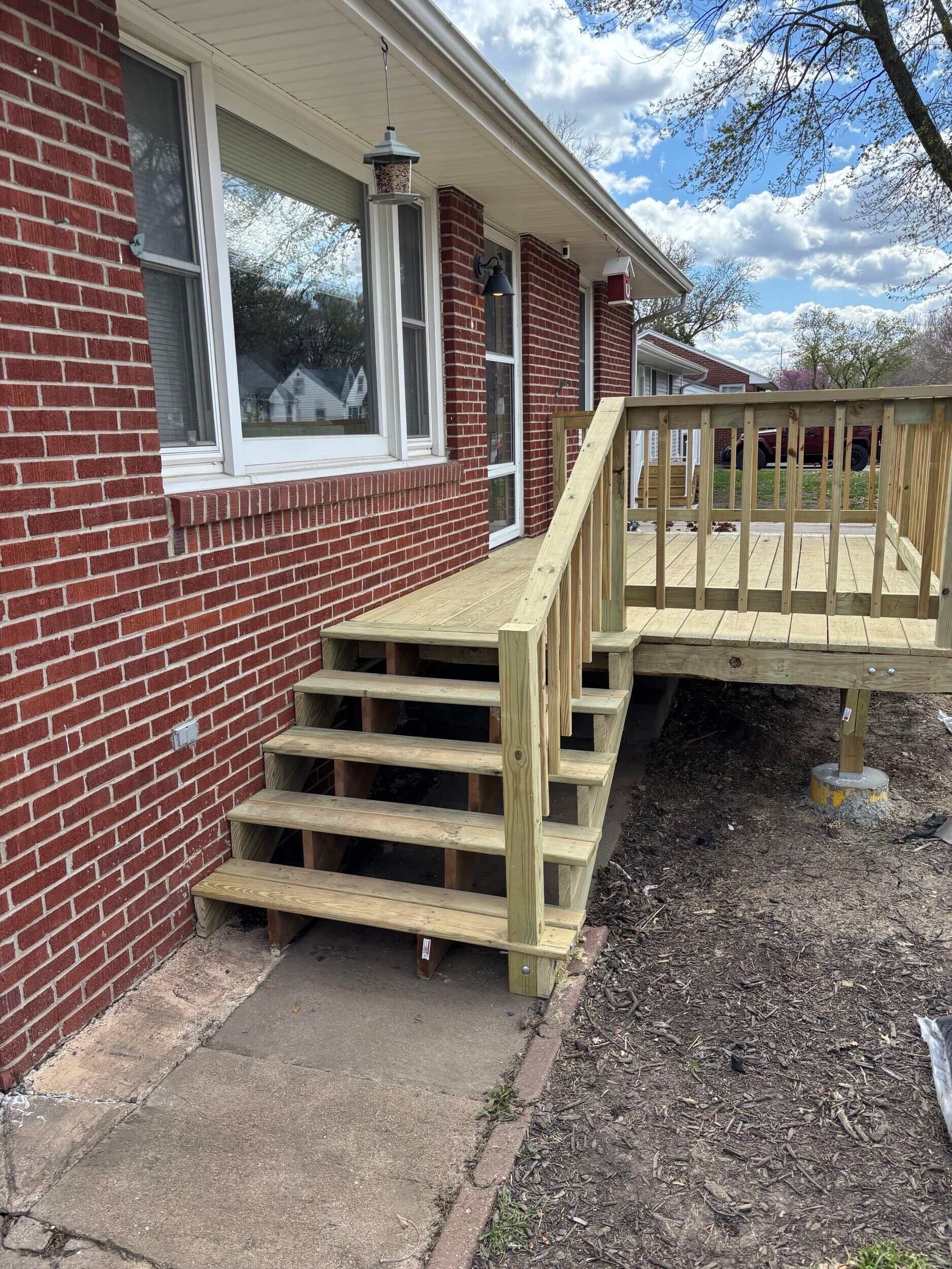 Wooden accessibility ramp and stairs beside a brick house exterior