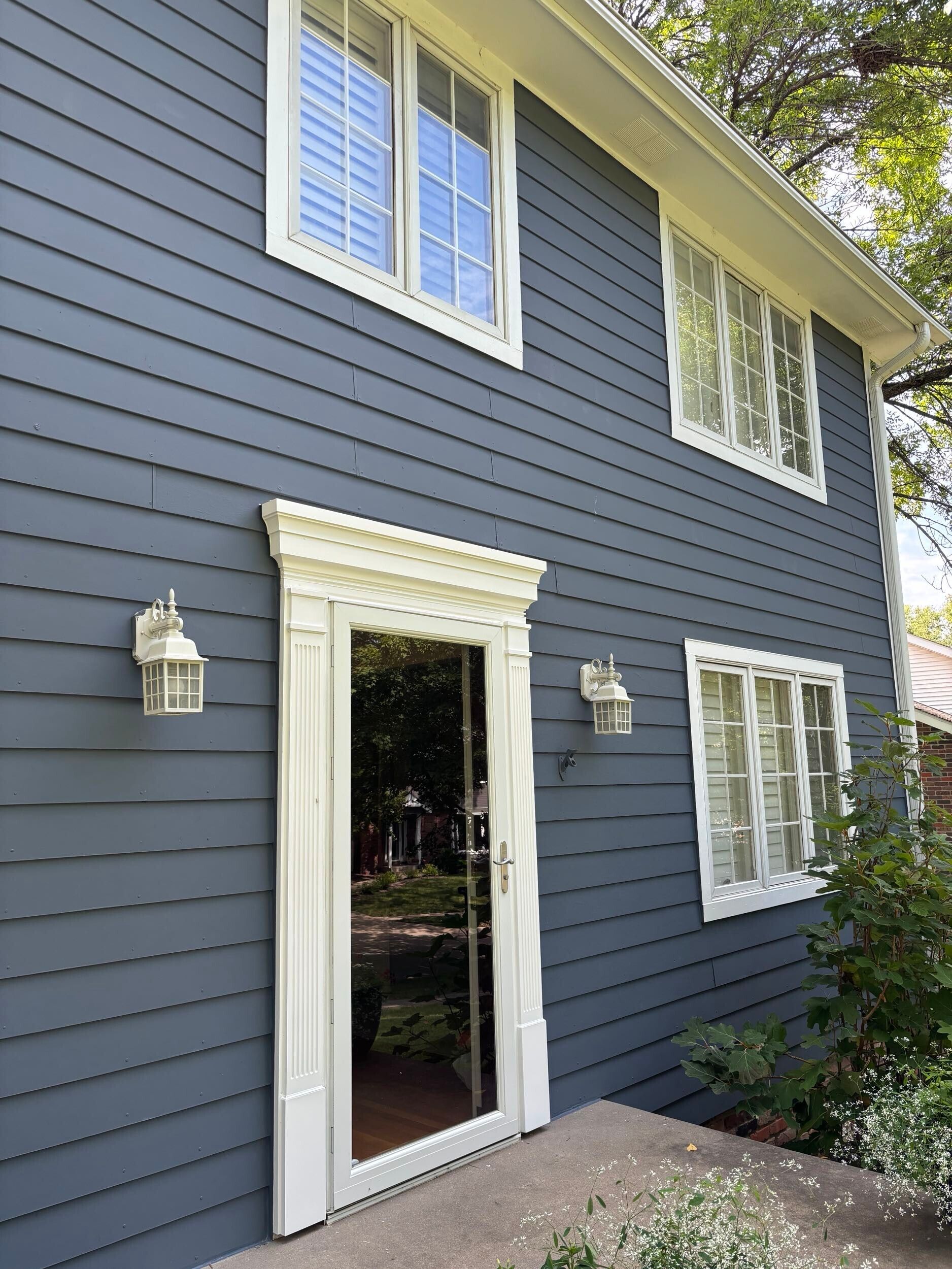Blue two-story house exterior with white-trimmed windows and a glass front door