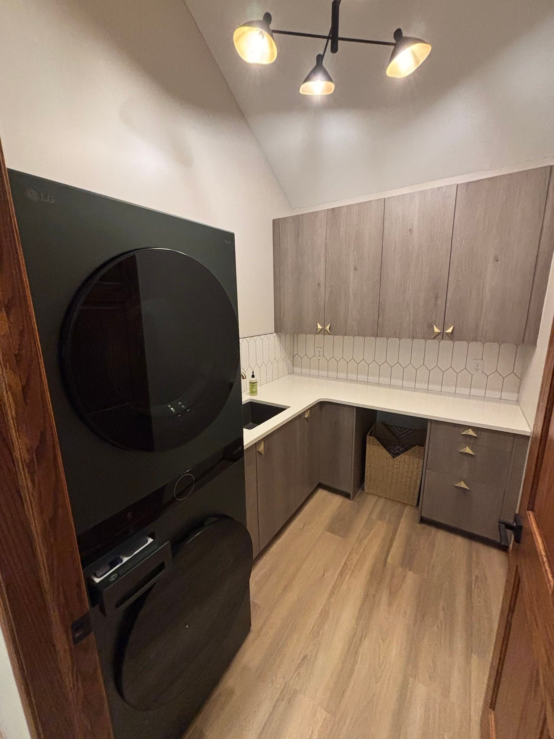 Small kitchen with black appliances, wood cabinets, white countertops, and a ceiling light.