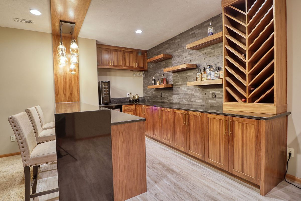 Modern kitchen with wood cabinets, stone backsplash, island seating, and a built-in wine rack.