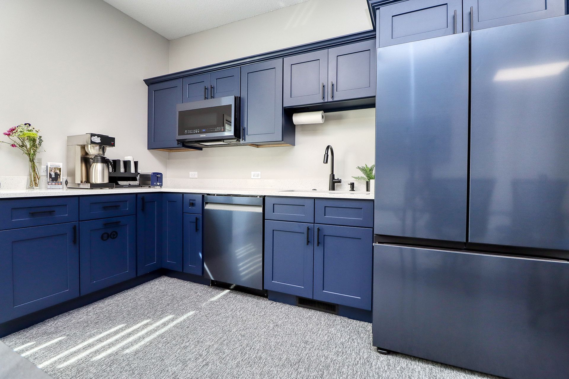 Modern kitchen with blue cabinets, stainless steel appliances, and speckled flooring